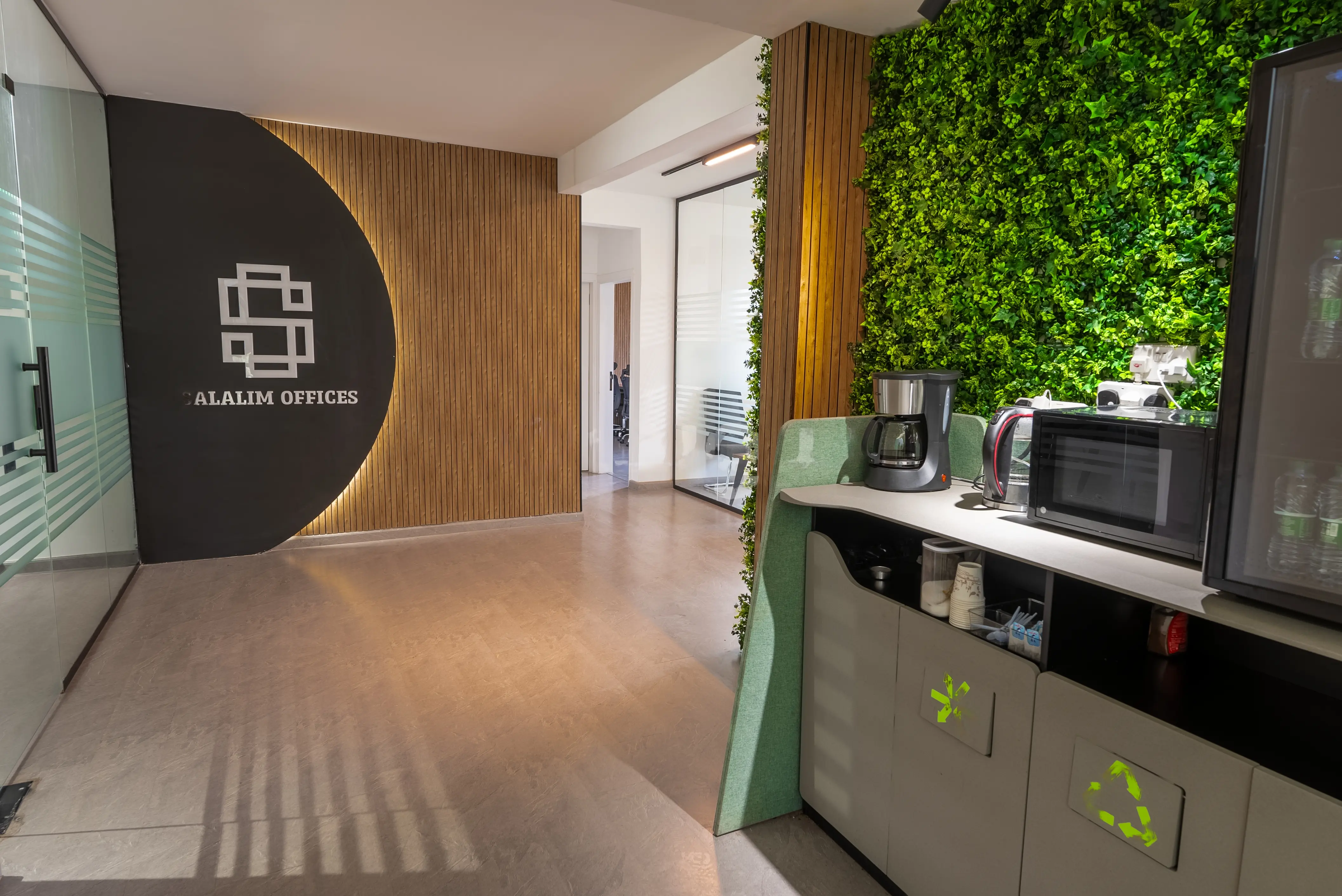 A modern office with a green accent wall and a refrigerator in the corner